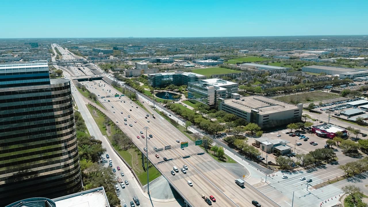 Modern glass office buildings, corporate office headquarters landmark in Westchase business district looking down busy Sam Houston Tollway and Richmond Avenue intersection, highway traffic aerial. USA